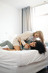 Happy, laughing and a lesbian couple in the bedroom in the morning for love and bonding. House, romance and gay or lgbt women on a bed for conversation, care and comfortable in a marriage together