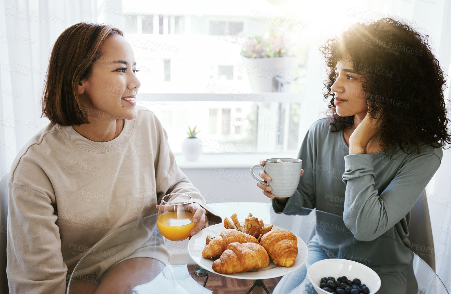 Buy stock photo Orange juice, coffee and happy lesbian couple in home at table bonding together. Drink, food and croissant of gay women in the morning for breakfast diet, eating and healthy interracial relationship