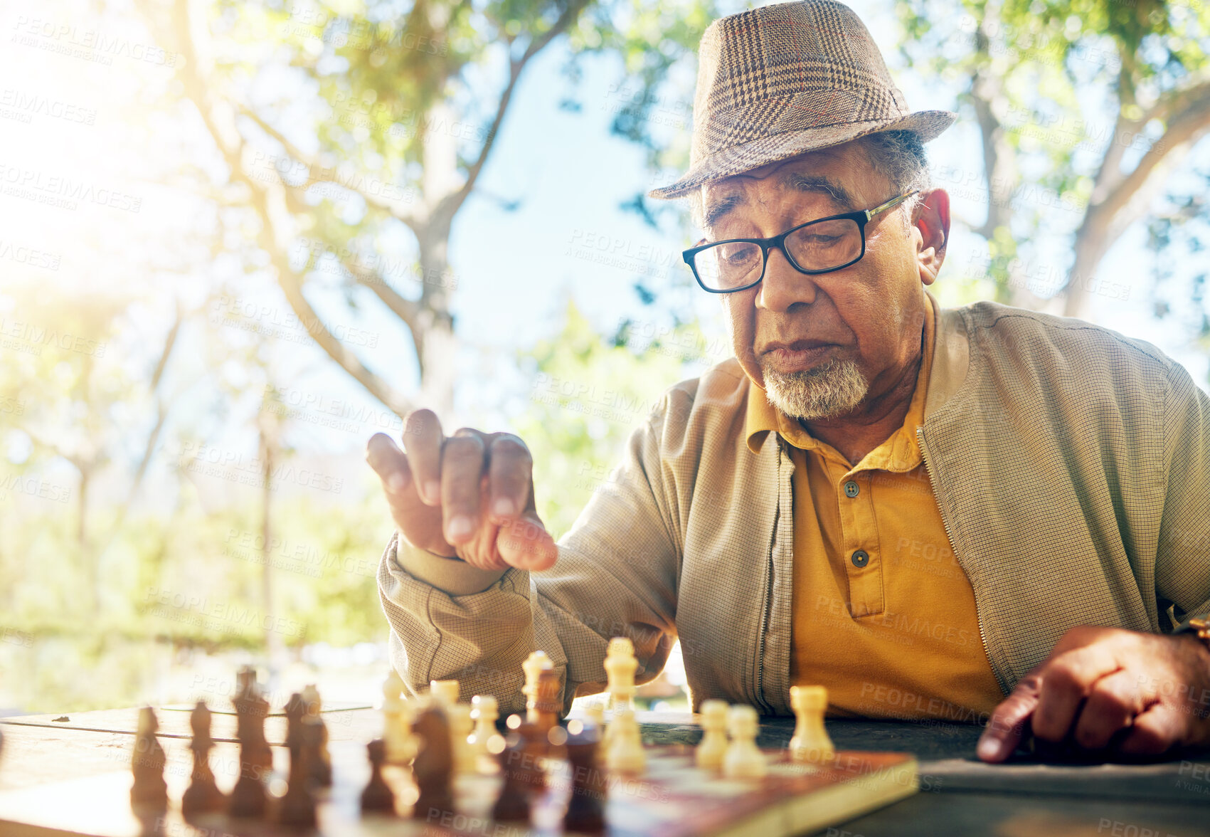 Buy stock photo Playing, chess and senior man outdoor with game of strategy and thinking in retirement for mental challenge. Boardgame, choice and elderly person in park, woods or nature and move piece in checkmate