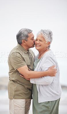 Buy stock photo Senior couple, kiss or hug on beach with smile, embrace and enjoying for retirement, happy or love. Senior citizen, romance and lovers with bond, happiness and vacation for travel, anniversary or fun