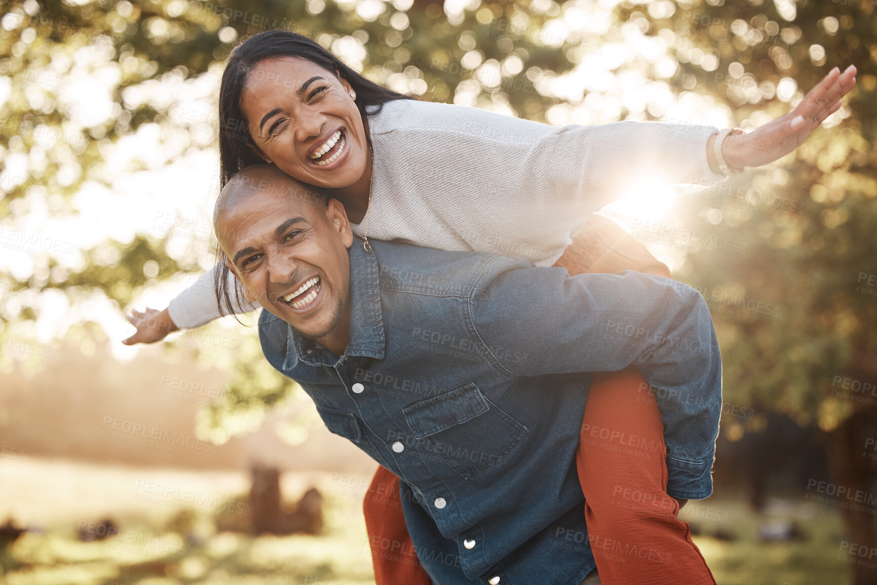 Buy stock photo Couple, park and happy with piggy back, portrait and airplane game in nature, holiday and bonding in summer. Man, woman and playful in backyard, freedom and vacation by trees with love in sunshine