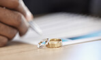 Divorce, rings and signature on paperwork for a lawyer, register wedding or writing on a contract. Table, closeup and a certificate, planning or legal documrnts for a commitment or engagement