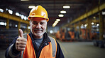 Confident mature older man with hardhat in shipping warehouse showing thumbsup at camera