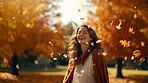 Joyful young woman happy in falling autumn leaves. Cheerful female walking in a park.