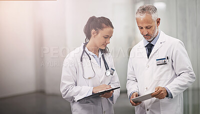 Buy stock photo Cropped shot of a mature doctor using his digital tablet to teach a female colleague