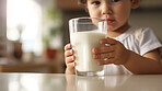 Toddler holding a glass of milk. close-up of baby with a glass of milk