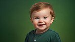 Portrait of a toddler posing against a green background. happy smiling boy