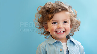 Portrait of a toddler posing against a blue background. happy smiling girl