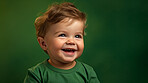 Portrait of a toddler posing against a green background. happy smiling boy