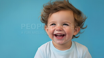 Portrait of a toddler posing against a blue background. happy smiling boy
