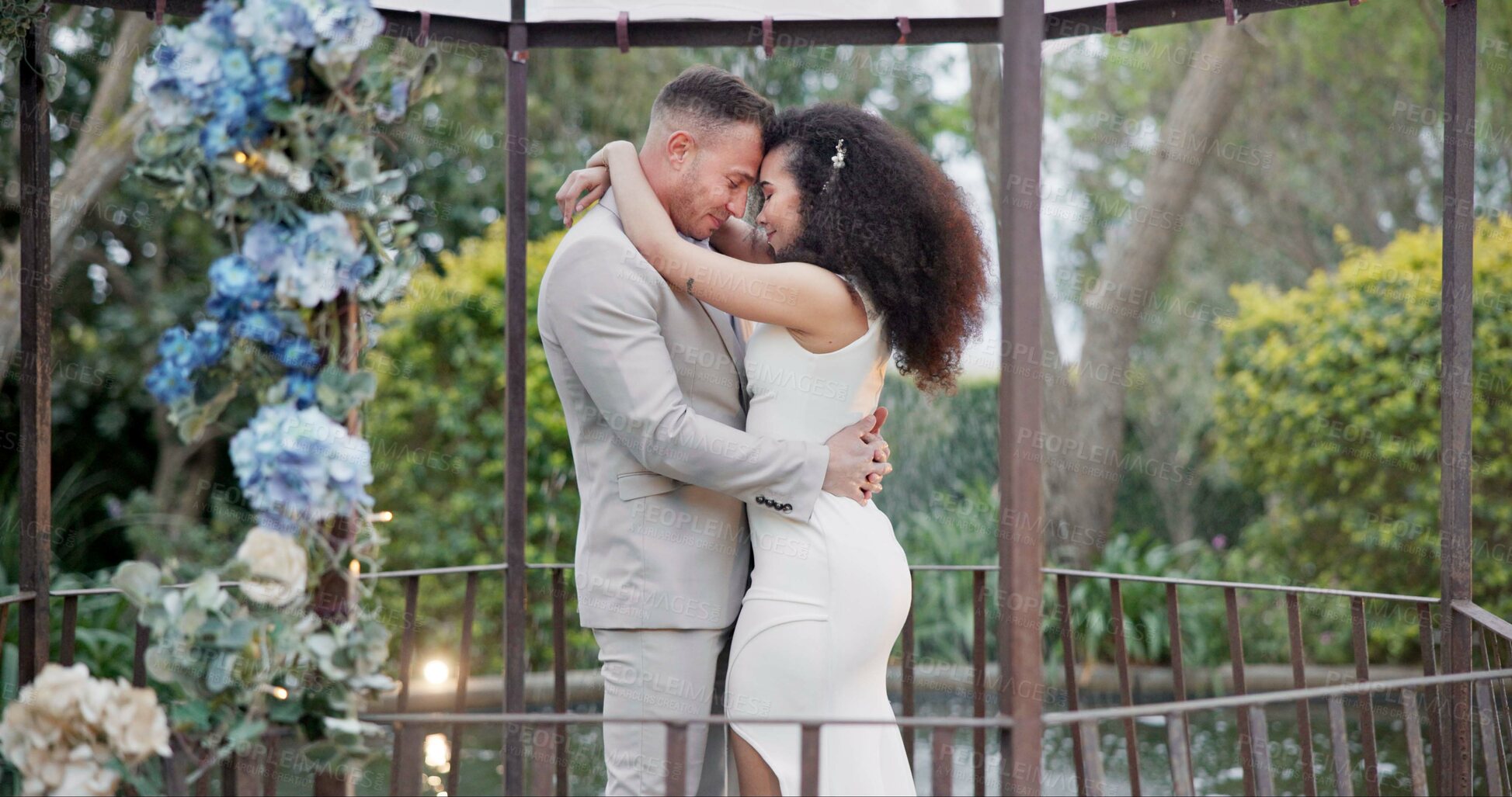 Buy stock photo Wedding, bride and groom dancing with hug and happiness at ceremony with life partner and commitment. Marriage, trust and people in interracial relationship, event decor and nature, love and care