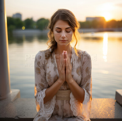 Prayer, woman on knees praying. Lake and sunset in background. Religion concept.
