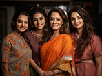 Proud Indian mother with daughters wearing traditional attire. Posing in home.