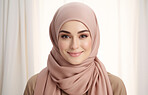 Portrait of young smiling muslim woman on clear backdrop. Wearing hijab. Religion concept.