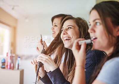 Buy stock photo Cropped shot of three young friends putting on makeup and styling their hair in the bathroom