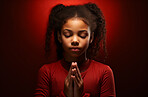 African American child praying. Studio portrait. Red backdrop. Religion concept.