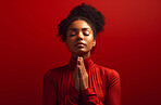 African American woman praying. Studio portrait. Red backdrop. Religion concept.