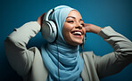 Happy muslim girl wearing headphones in studio portrait. Religion concept.