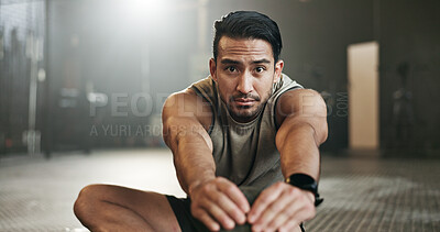 Man stretching on floor of gym for strong body, muscle development or balance in power fitness. Commitment, motivation and focus on ground, bodybuilder in energy training workout and exercise mindset