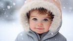 Toddler boy wearing a coat, playing in the winter snow during the holiday season