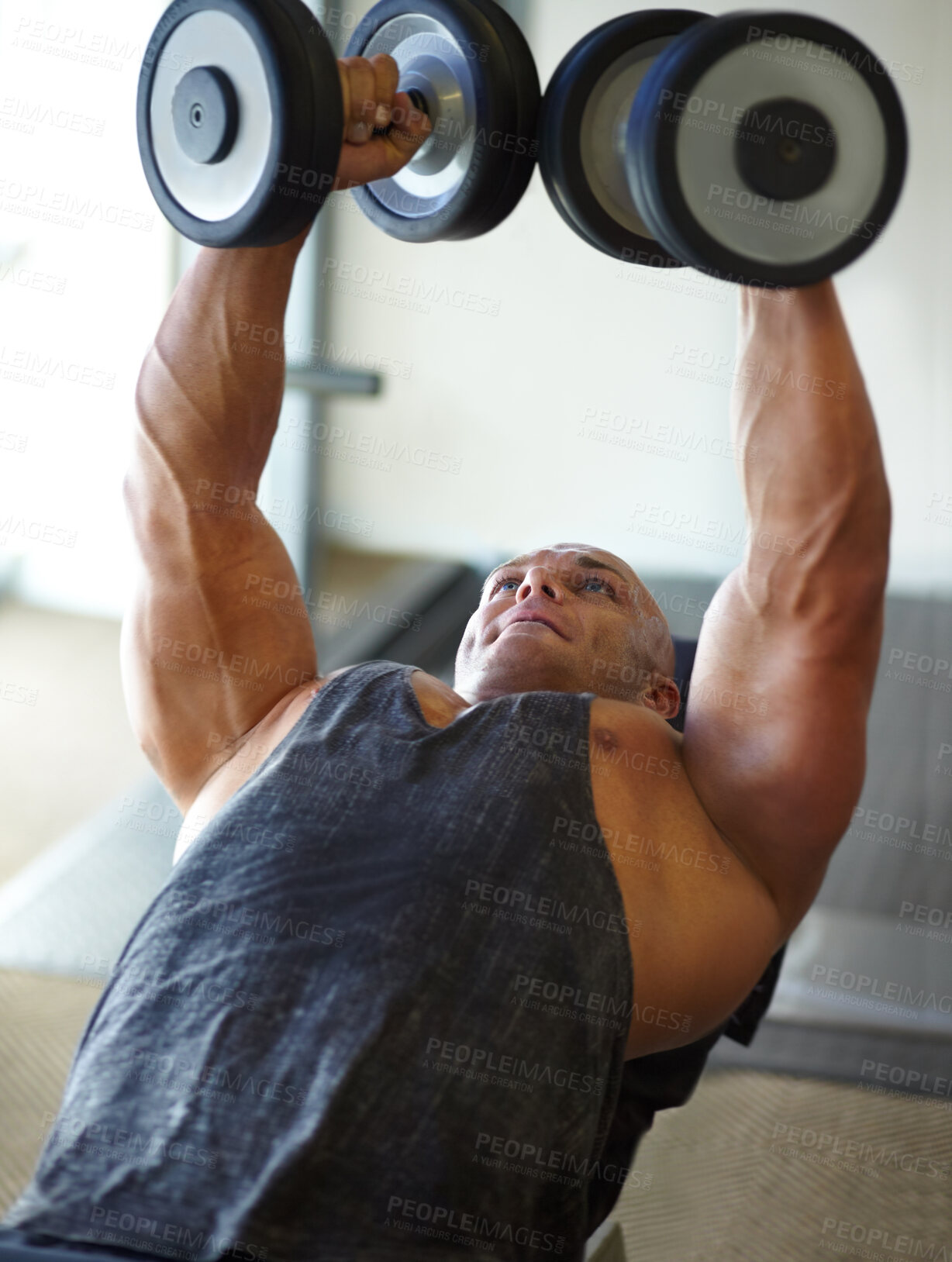 Buy stock photo Shot of a male bodybuilder lifting weights at the gym