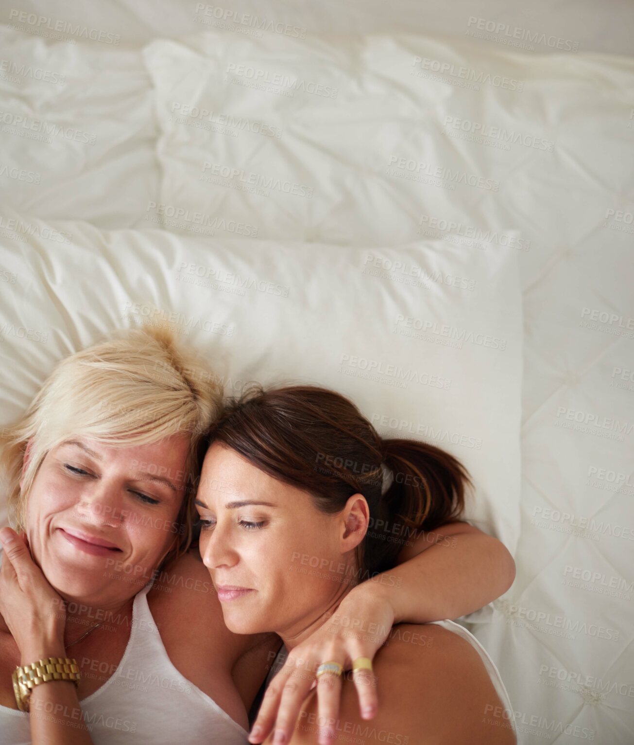 Buy stock photo High angle shot of a loving lesbian couple lying in bed