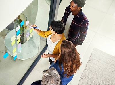 Buy stock photo Cropped shot of coworkers brainstorming using sticky notes on a glass wall in an office