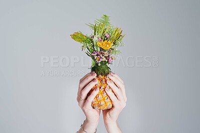 Buy stock photo Shot of an unrecognizable woman holding a pineapple stuffed with flowers