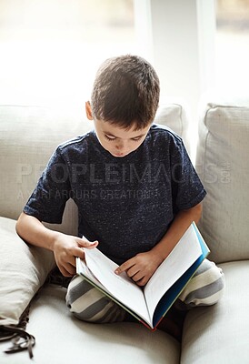 Buy stock photo Hobby, boy and reading on sofa, relax and happy on weekend, break and learning. Male child, kid and book for fun, education and story time on couch in living room, happiness and child development