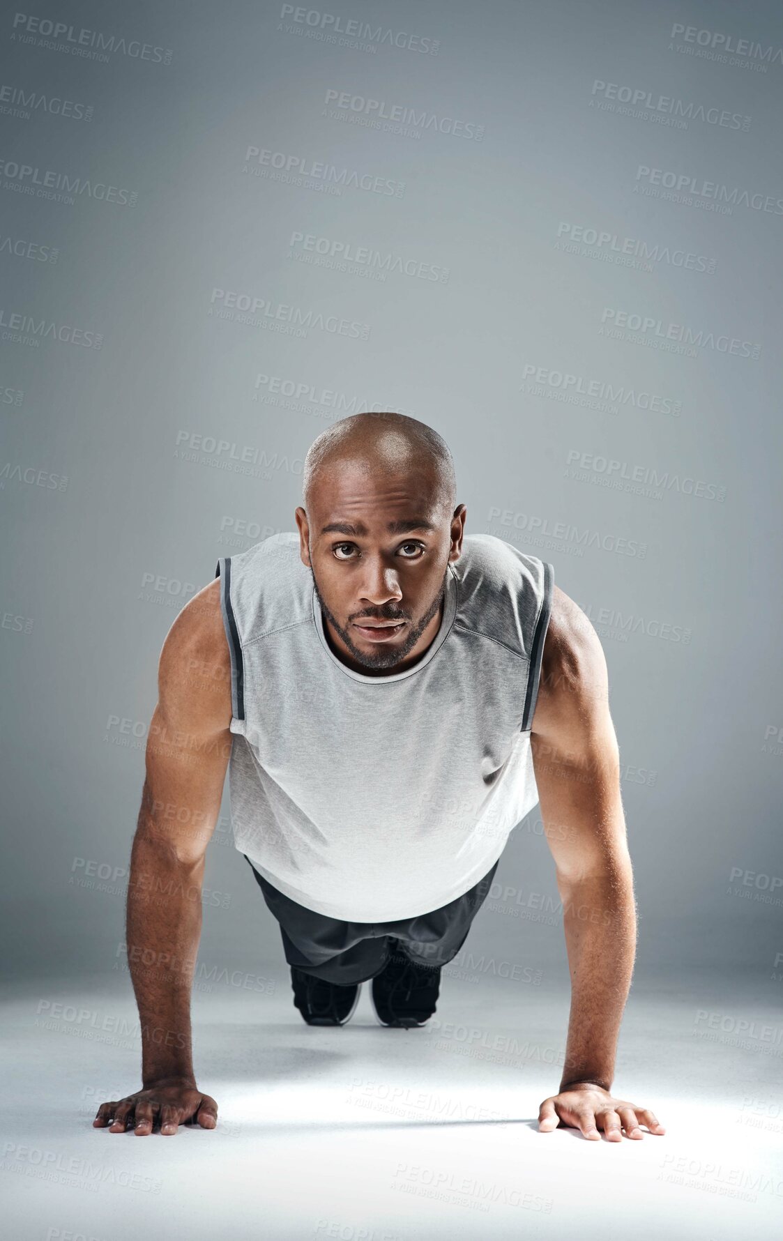 Buy stock photo Shot of a sporty young man doing push ups against a grey background