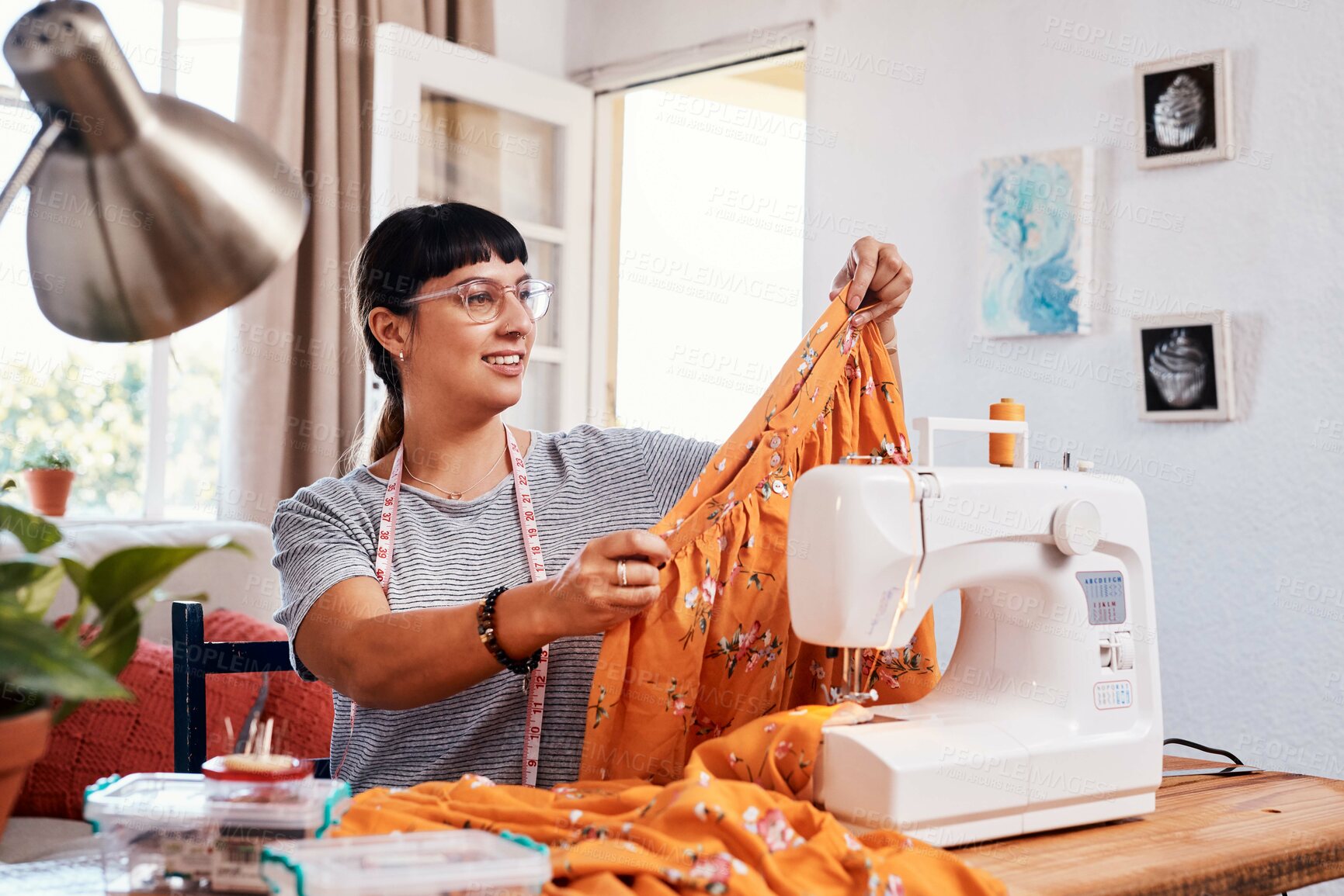 Buy stock photo Shot of a beautiful young woman working on a garment at home