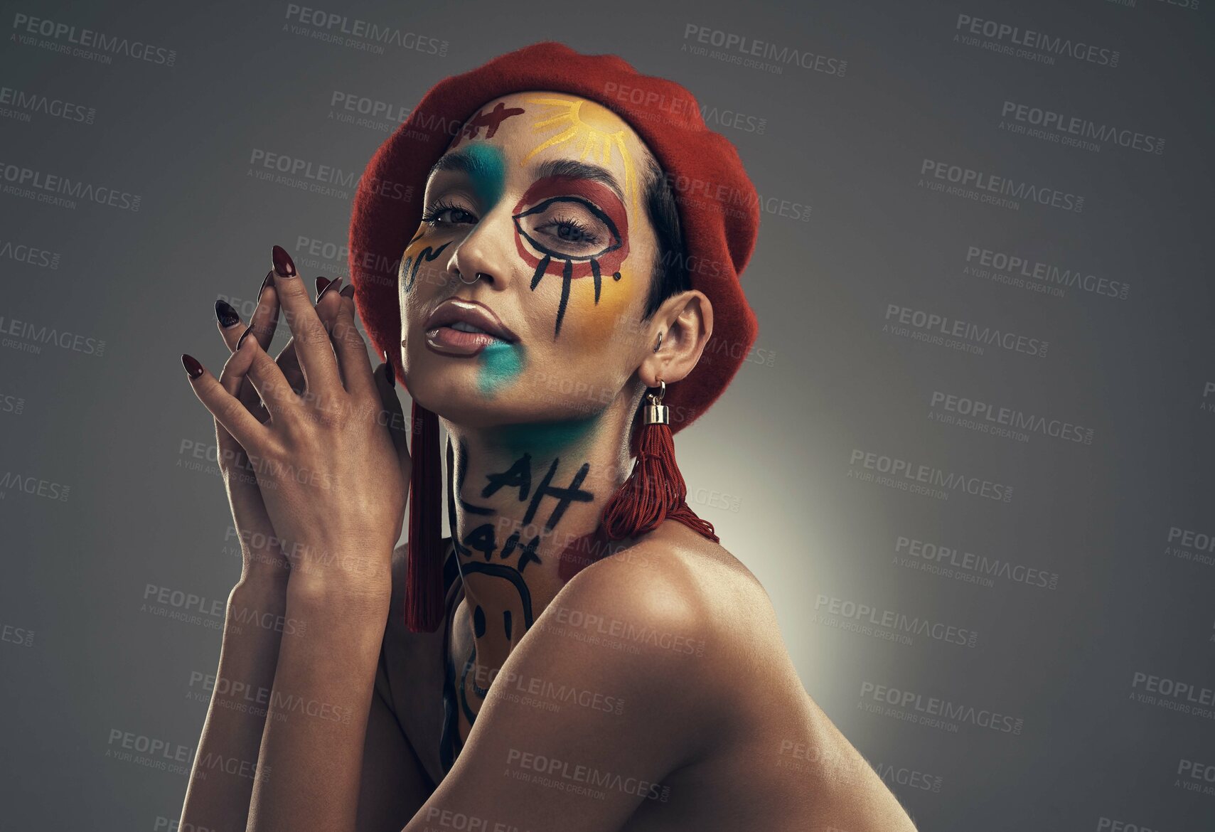 Buy stock photo Studio shot of a young woman posing with paint on her face on a grey background