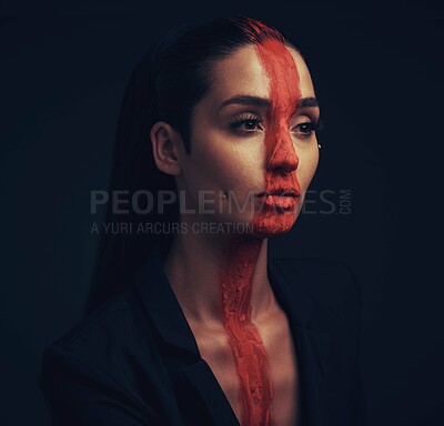 Buy stock photo Studio shot of a young woman posing with paint on her face on a black background