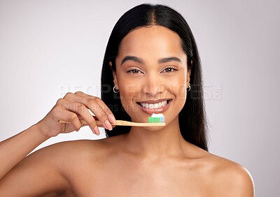 Buy stock photo Studio portrait of an attractive young woman brushing her teeth against a pink background
