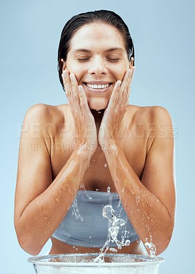 Buy stock photo Studio shot of an attractive young woman washing her face against a blue background