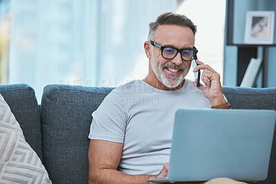 Buy stock photo Shot of a mature businessman working from home while using his laptop and making a call