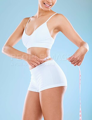 Buy stock photo Cropped shot of an unrecognizable woman standing in the studio and using a measuring tape around her waist