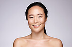 Skincare, happy beauty and woman with a glow, marketing spa and dermatology on a grey studio background with mockup. Luxury, cosmetics and face portrait of an Asian model smile for advertising skin
