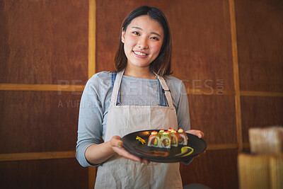 Restaurant, portrait and female waitress with sushi for serving a food order with a smile. Happy, lunch and young Asian server with a plate of a Japanese recipe or meal at a traditional cuisine cafe.