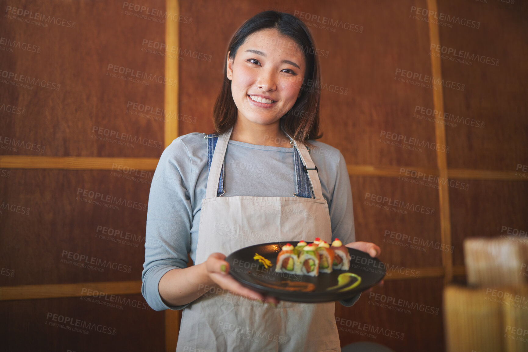 Buy stock photo Restaurant, portrait and female waitress with sushi for serving a food order with a smile. Happy, lunch and young Asian server with a plate of a Japanese recipe or meal at a traditional cuisine cafe.