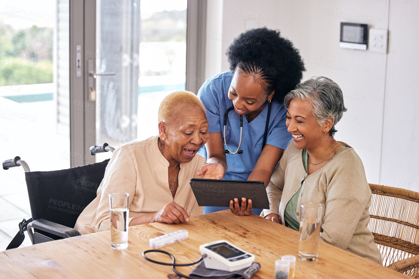 Buy stock photo Tablet, smile and an assisted living caregiver with old women in the kitchen of a retirement home for consulting. Blood pressure, medical and an african nurse showing information to patient friends