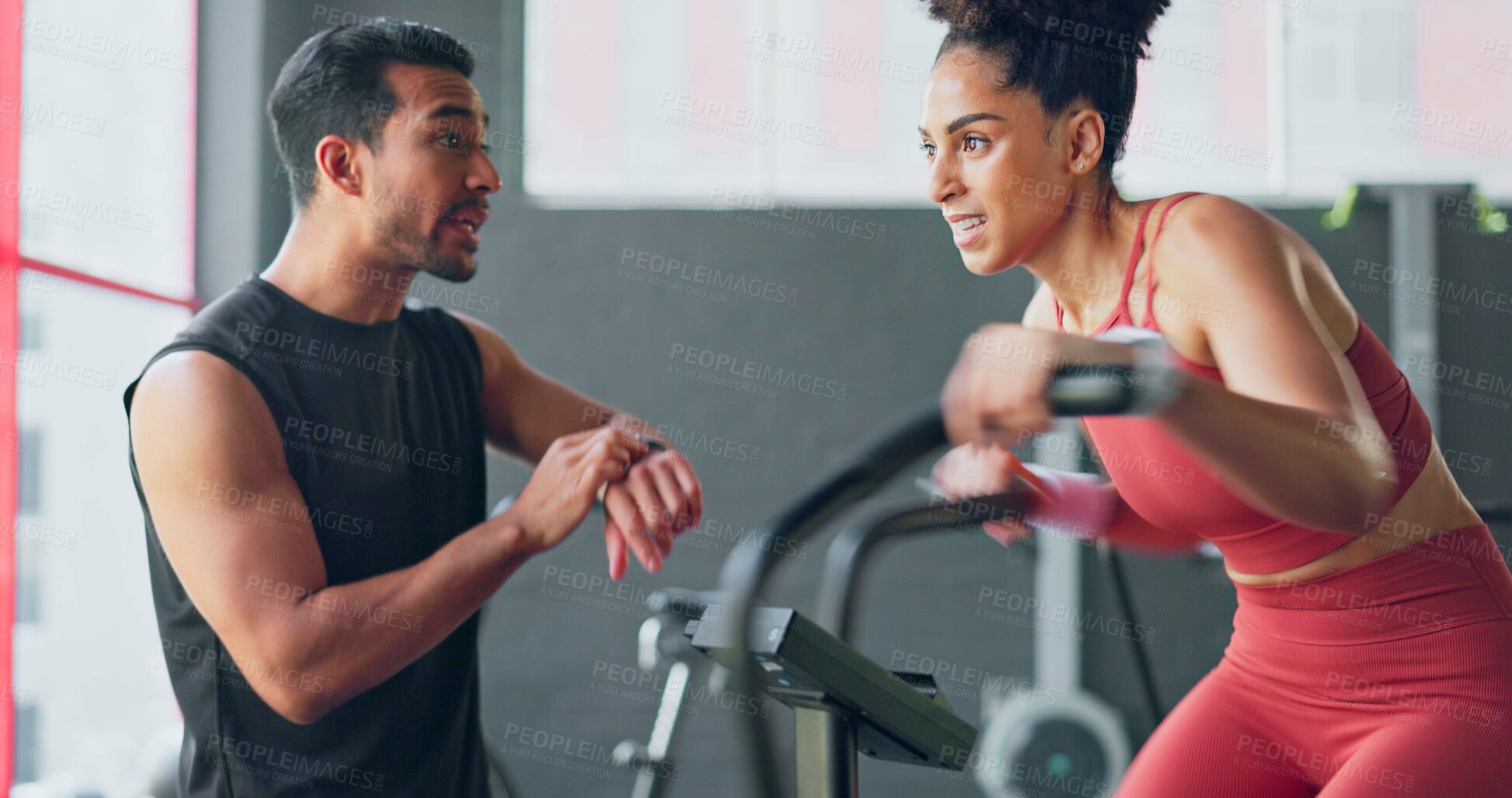 Buy stock photo Fitness, training on an exercise bike and a woman with her coach in the gym to time her speed on a sports watch. Exercise, motivation and a personal trainer with a young athlete for workout support