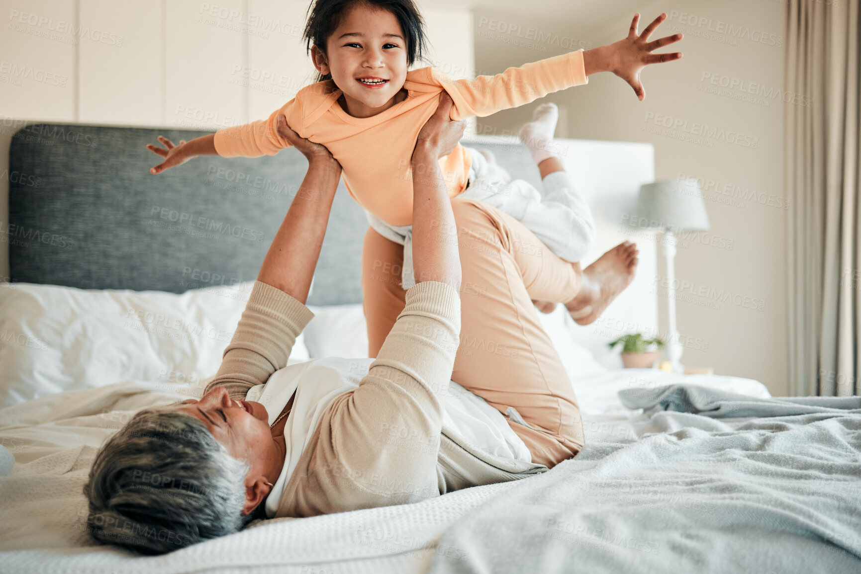 Buy stock photo Woman, girl child and bed for airplane game, portrait and smile with lift, flying and bonding in family home. Senior lady, kid and plane with flight, love and care with freedom, balance and fantasy