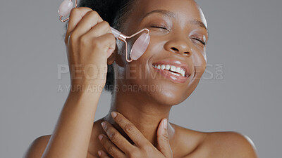 Buy stock photo Black woman, face with roller and massage for skincare and beauty, natural cosmetics and treatment on white background. Wellness, dermatology and skin glow, rose quartz crystal and tools in studio