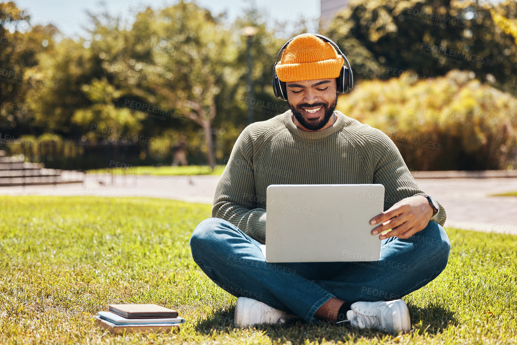 Buy stock photo Student, laptop and headphones in university park, college or school for research, studying and e learning on grass. African man on computer, listening to music or campus podcast for online education