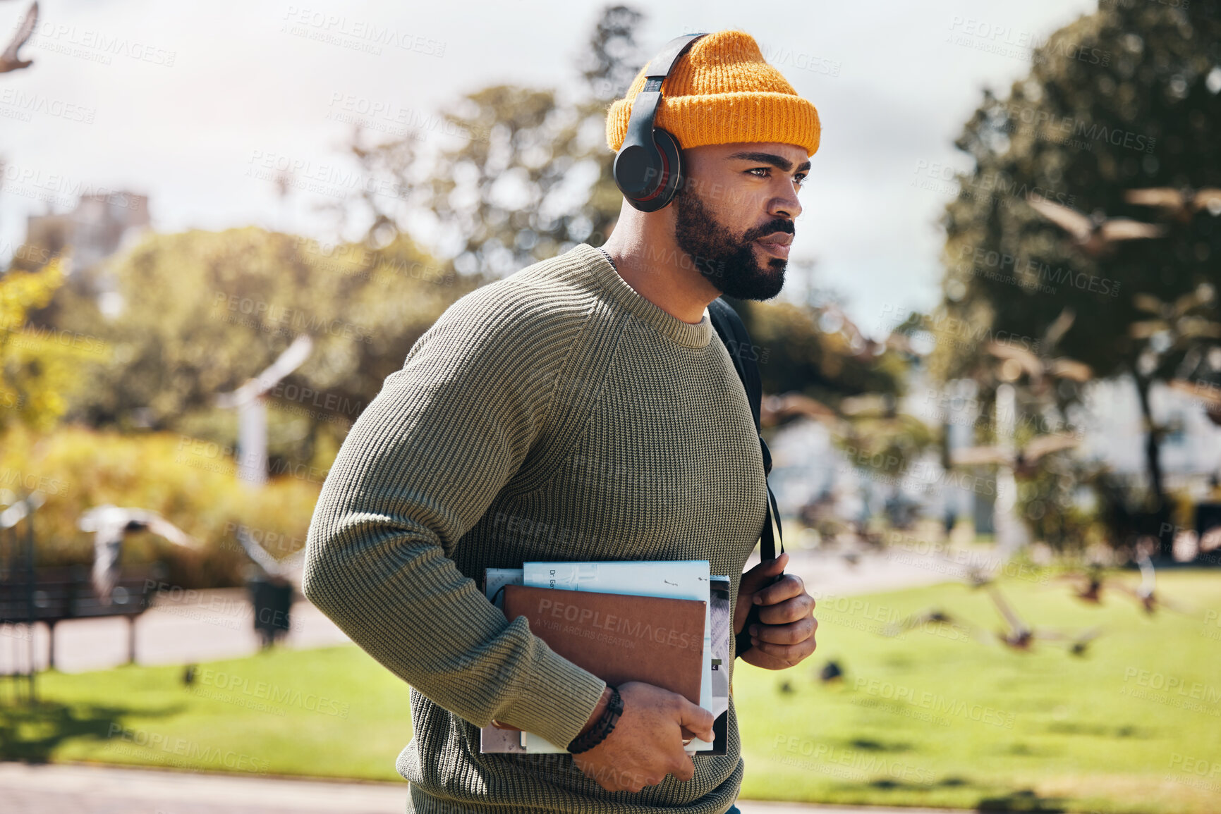 Buy stock photo Man on campus, university books and headphones on morning commute for education with backpack. Learning, studying and college student in park with podcast, music or streaming online lecture on walk.