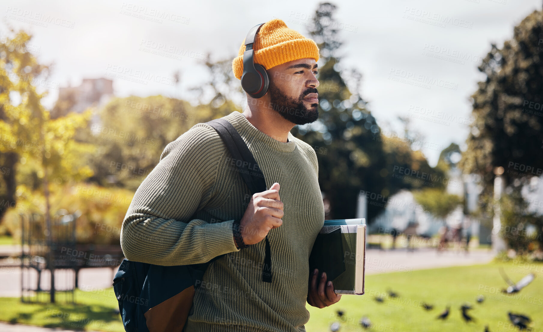 Buy stock photo Man on campus, walking with books and headphones on morning commute for education with backpack. Learning, studying and college student in park listening to podcast, music or streaming online lecture