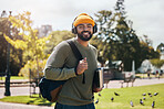 Portrait of happy man on campus with books, headphones and backpack on morning commute for education. Learning, studying and college student in park with podcast, music or streaming online on walk.