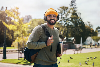 Buy stock photo Portrait of happy man on campus with books, headphones and backpack on morning commute for education. Learning, studying and college student in park with podcast, music or streaming online on walk.