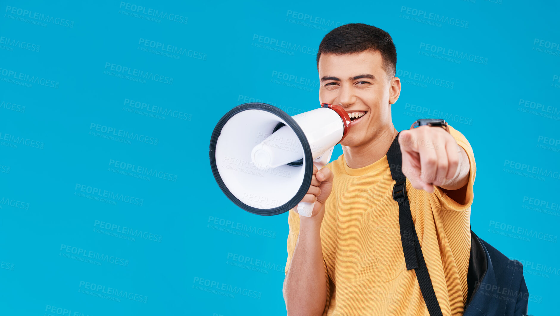 Buy stock photo Megaphone, mockup and portrait of man in studio pointing for announcement, speech or rally. Smile, protest and male student from Canada with bullhorn for communication isolated by blue background.